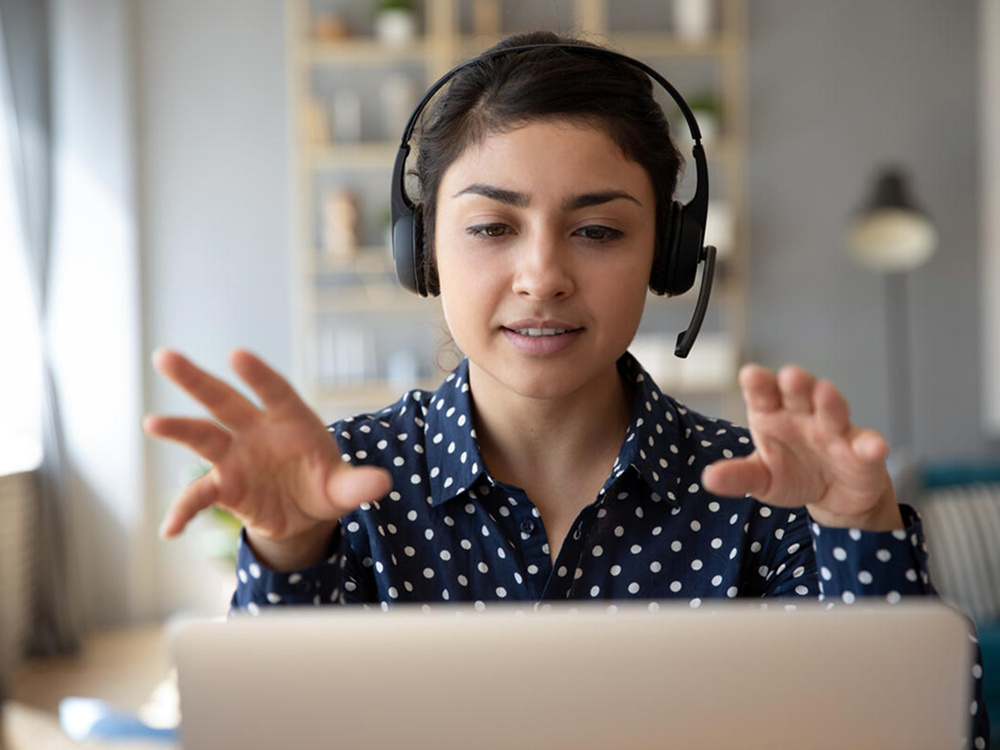 A photo of a woman wearing a headset and looking at a computer monitor